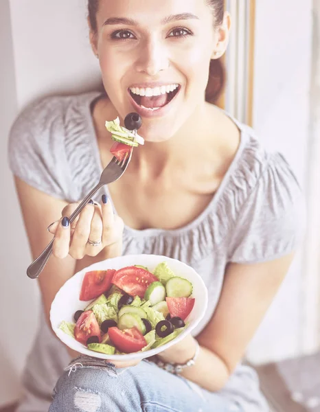 Une belle fille mangeant des aliments sains, assise près de la fenêtre — Photo