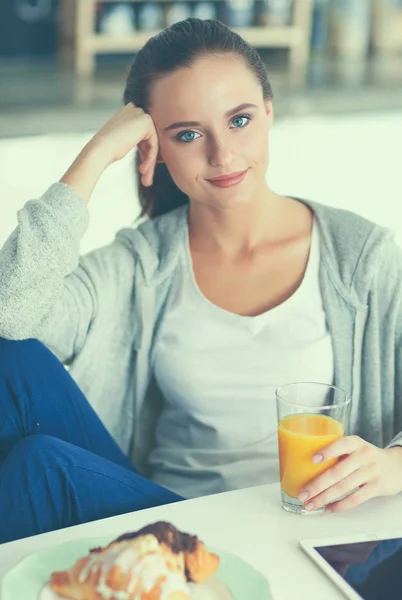 Młoda kobieta z sokiem pomarańczowym i tabletką w kuchni — Zdjęcie stockowe