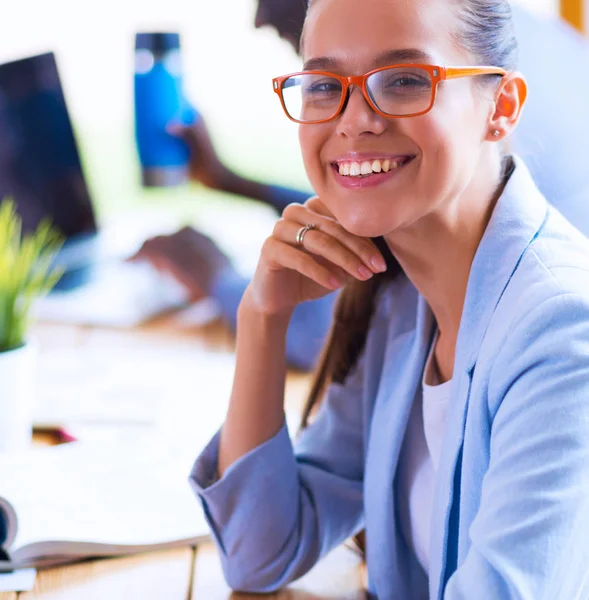 İş kadını ofisinde tablet bilgisayar kullanarak oturuyor.