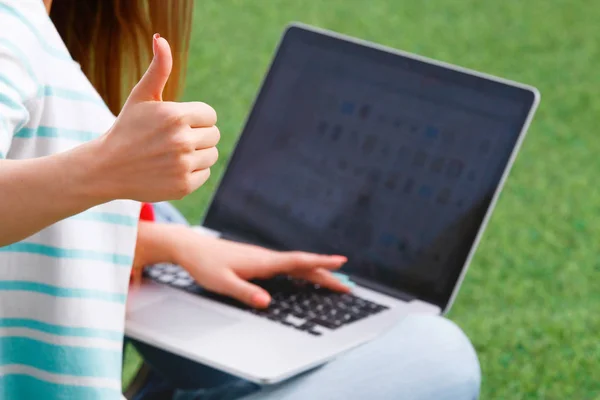 Young woman with laptop sitting on green grass — Stock Photo, Image