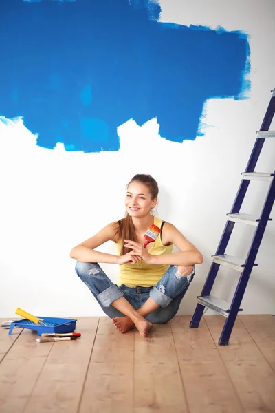 Portrét ženy malíře sedí na podlaze blízko zdi po malování — Stock fotografie