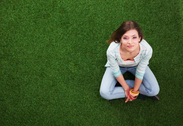 Mooie jonge vrouw zittend op het gras — Stockfoto