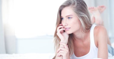 Güzel bir kadın yatağında uzanıyor.