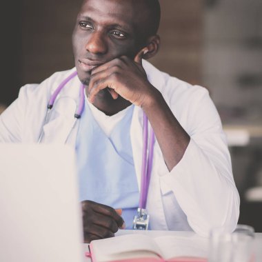 Masada dizüstü bilgisayarda çalışan genç bir Afrikalı doktor.