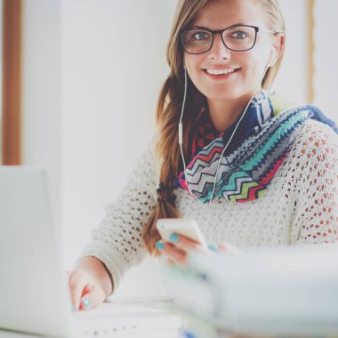 Kitapların arasında masa başında oturan genç bir kadın.