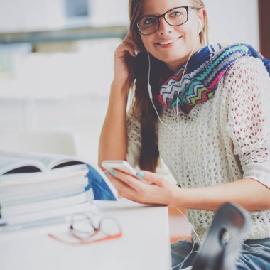 Kitapların arasında masa başında oturan genç bir kadın.