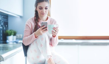 modern mutfakta otururken cep telefonu kullanan kadın