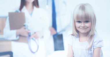 Kadın doktor ameliyatta steteskopla çocuğu muayene ediyor.