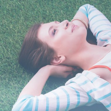 güzel bir genç kadın yeşil çim üzerinde yalan