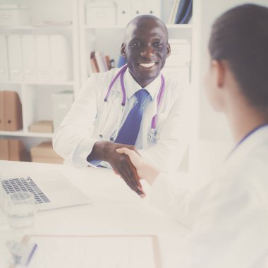 Ofiste tokalaşırken gülümseyen iki genç doktor.