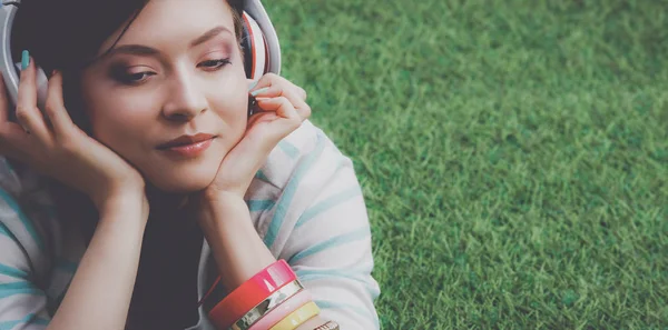 听音乐躺在绿草地上的女人 — 图库照片