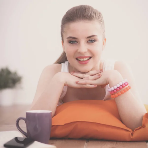 Jeune femme souriante couchée sur un sol avec oreiller — Photo