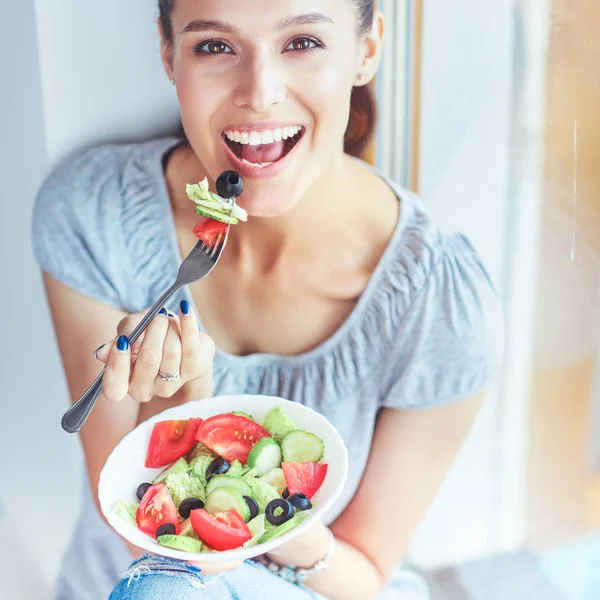 A beautiful girl eating healthy food, sitting near window — Stock Photo, Image