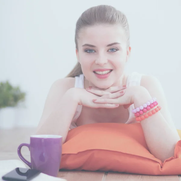 Smiling young woman lying on a floor with pillow — Stock Photo, Image