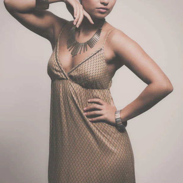 Ung kvinna som bär en beige klänning stående — Stockfoto