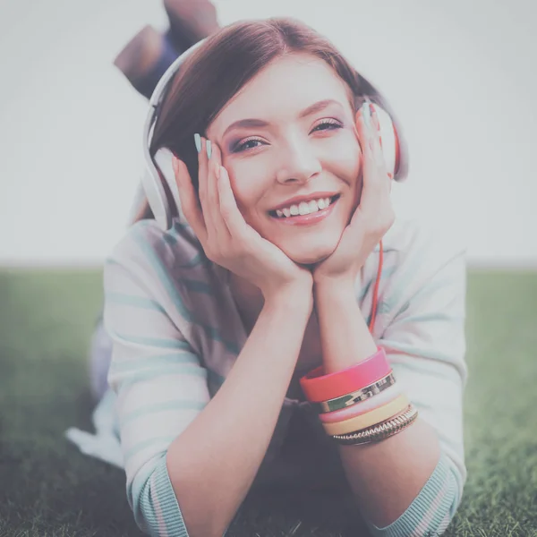 Mujer escuchando la música tumbada sobre hierba verde —  Fotos de Stock