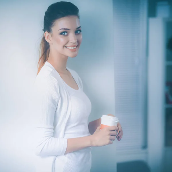 Attraktive junge Geschäftsfrau steht an Wand im Büro — Stockfoto