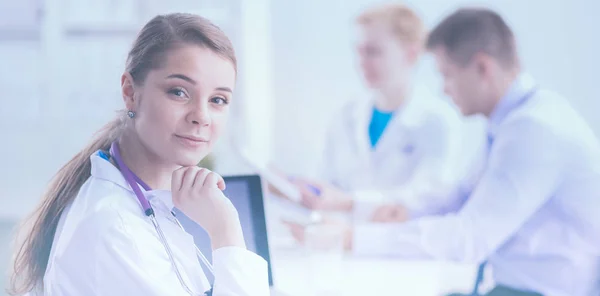 Belle jeune femme médecin souriante assise au bureau — Photo