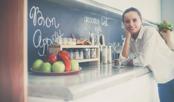 Porträtt av ung kvinna som står mot kök bakgrund — Stockfoto