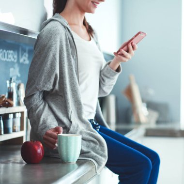 modern mutfakta otururken cep telefonu kullanan kadın