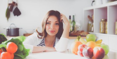 Mutfakta masanın yanında duran genç bir kadın.