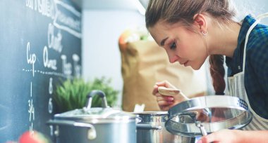 Mutfakta sobanın yanında duran genç bir kadın.