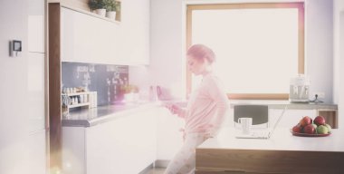 Güzel bir kadın mutfakta pasta pişiriyor. Masanın yanında duruyor.