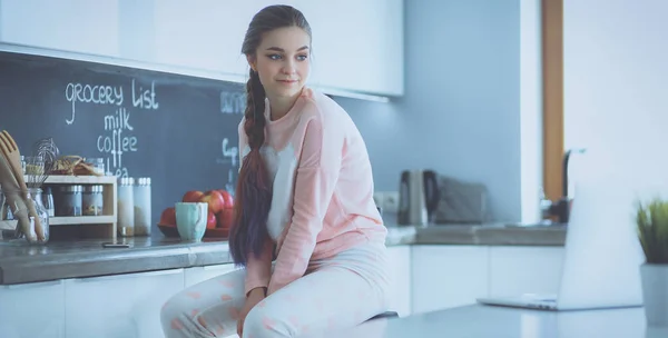 Молодая женщина сидит рядом со столом на кухне — стоковое фото