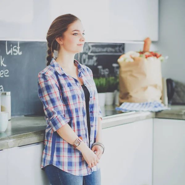 Retrato de mujer joven de pie con los brazos cruzados contra el fondo de la cocina —  Fotos de Stock