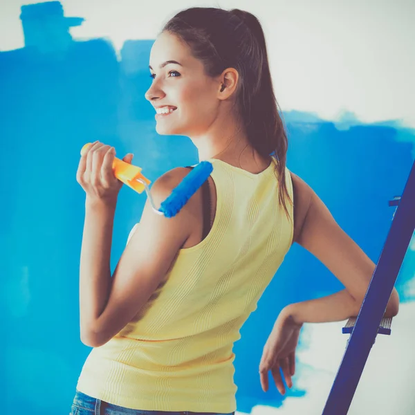 Gelukkig mooie jonge vrouw doet wandschildering, permanent in de buurt van ladder — Stockfoto