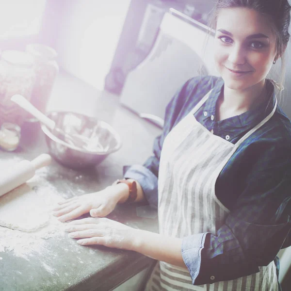 Güzel bir kadın mutfakta pasta pişiriyor. Masanın yanında duruyor.