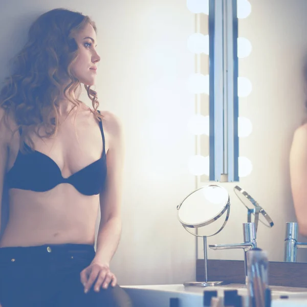 Young woman looking herself in the mirror on bathroom — Stock Photo, Image