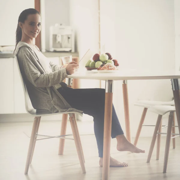 Ung kvinna med apelsinjuice och tablett i köket — Stockfoto