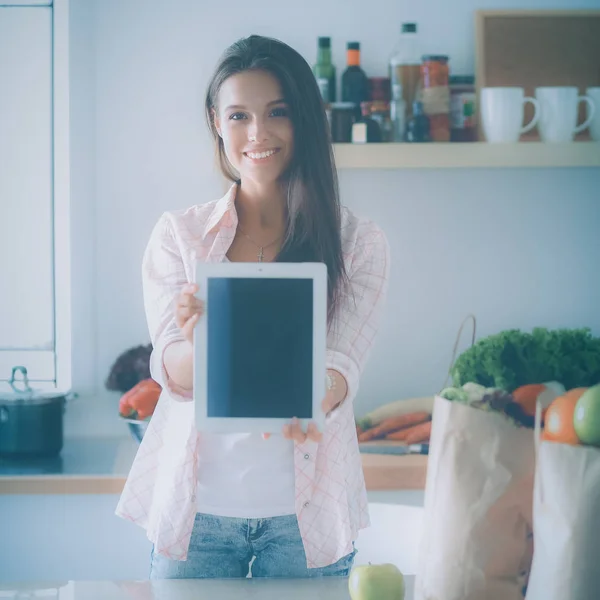 年轻女人在厨房里用平板电脑做饭 — 图库照片