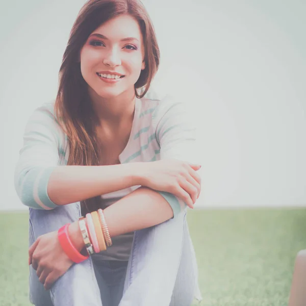 Beautiful young woman sitting on the green grass — Stock Photo, Image