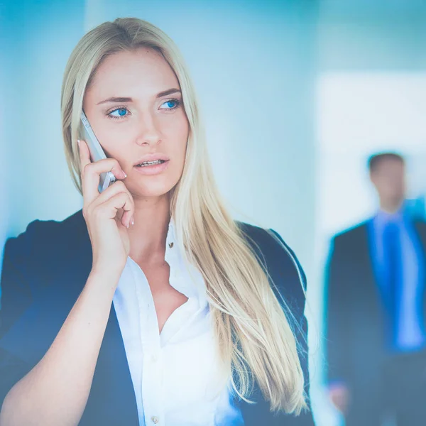 Zakenvrouw staat tegen kantoorraam te praten op mobiele telefoon — Stockfoto