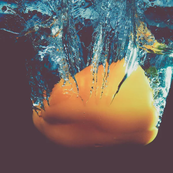 Fresh yellow paprika splash in water on black background — Stock Photo, Image