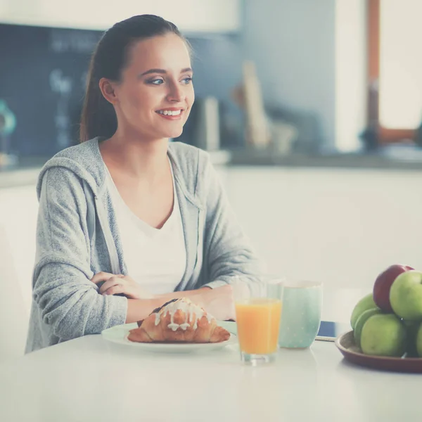 Ung kvinna med apelsinjuice och tablett i köket — Stockfoto