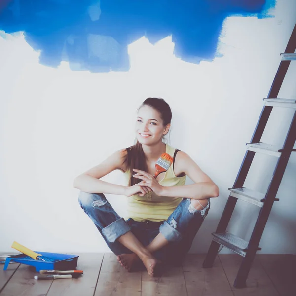 Portrait of female painter sitting on floor near wall after painting — Stock Photo, Image