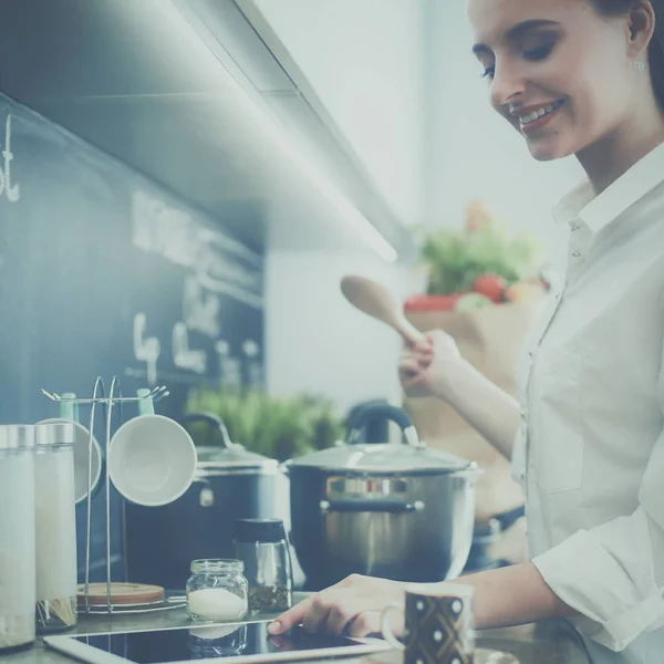 Mujer joven parada junto a la estufa en la cocina — Foto de Stock