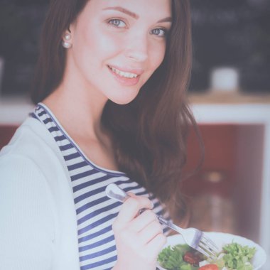 Genç bayan mutfakta masanın yanında oturuyor.