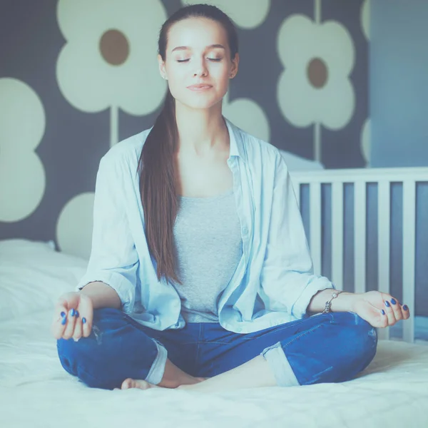 Young woman sitting on the bed near childrens cot — Stock Photo, Image