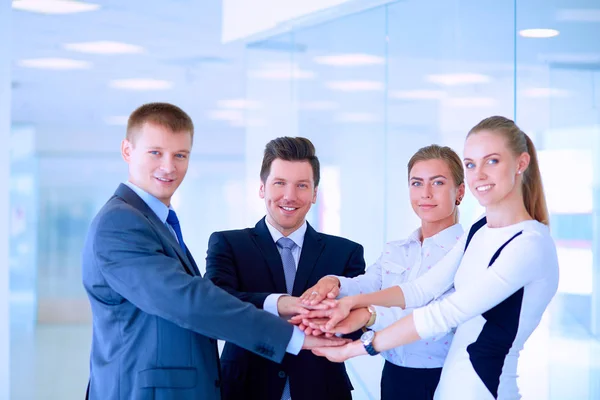 Business team joining hands together standing in office — Stock Photo, Image