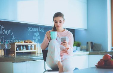 modern mutfakta otururken cep telefonu kullanan kadın