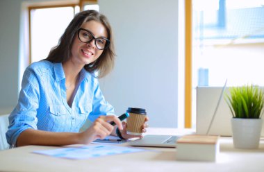 Dizüstü bilgisayar ekranına bakarak office tablosunda oturan genç kadın