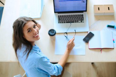 Dizüstü bilgisayar ekranına bakarak office tablosunda oturan genç kadın