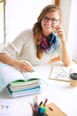 Kitapların arasında masa başında oturan genç bir kadın.