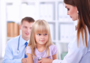 Kadın doktor ameliyatta steteskopla çocuğu muayene ediyor.