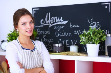 Mutfakta masanın yanında duran genç bir kadın.