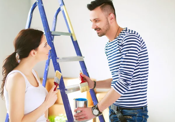 Retrato feliz sorrindo jovem casal pintura parede interior da nova casa — Fotografia de Stock